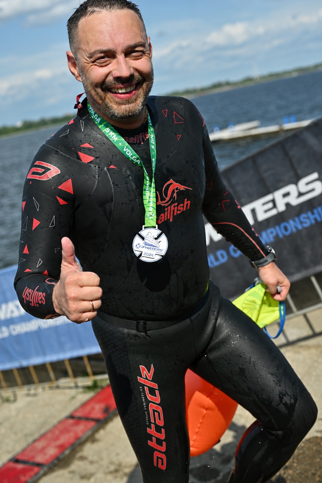 Участник заплыва показывает медаль после финиша